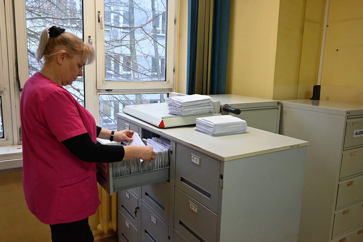 Rejestratorka przy szufladach z kartami pacjentów.